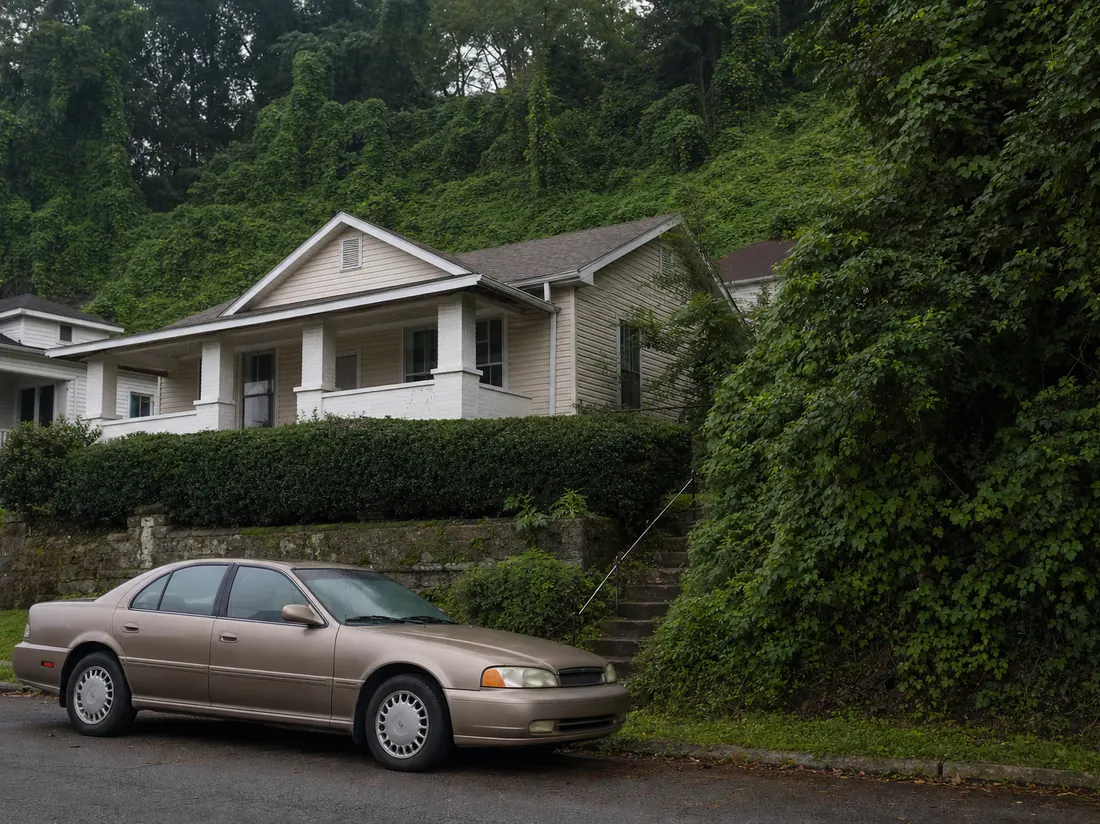 Older sedan at a Birmingham bungalow on a hillside street with kudzu-covered slope behind - selling a car in Birmingham