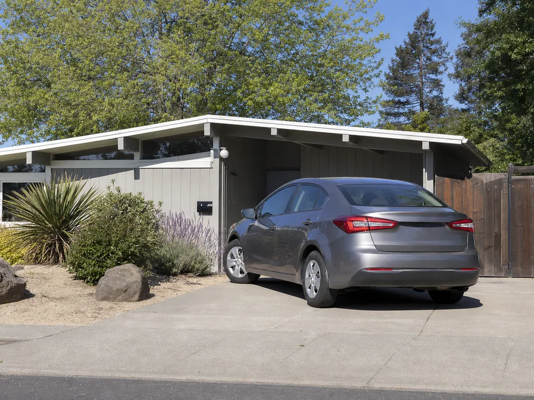 Compact sedan in the driveway of a modest San Jose Eichler-style home with a low roofline - selling a car in San Jose
