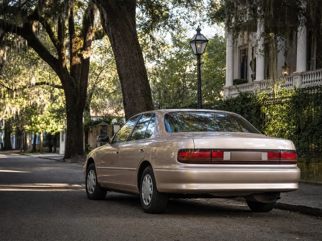 Older tan sedan parked beneath moss-draped live oaks on a Savannah street - selling a car in Savannah