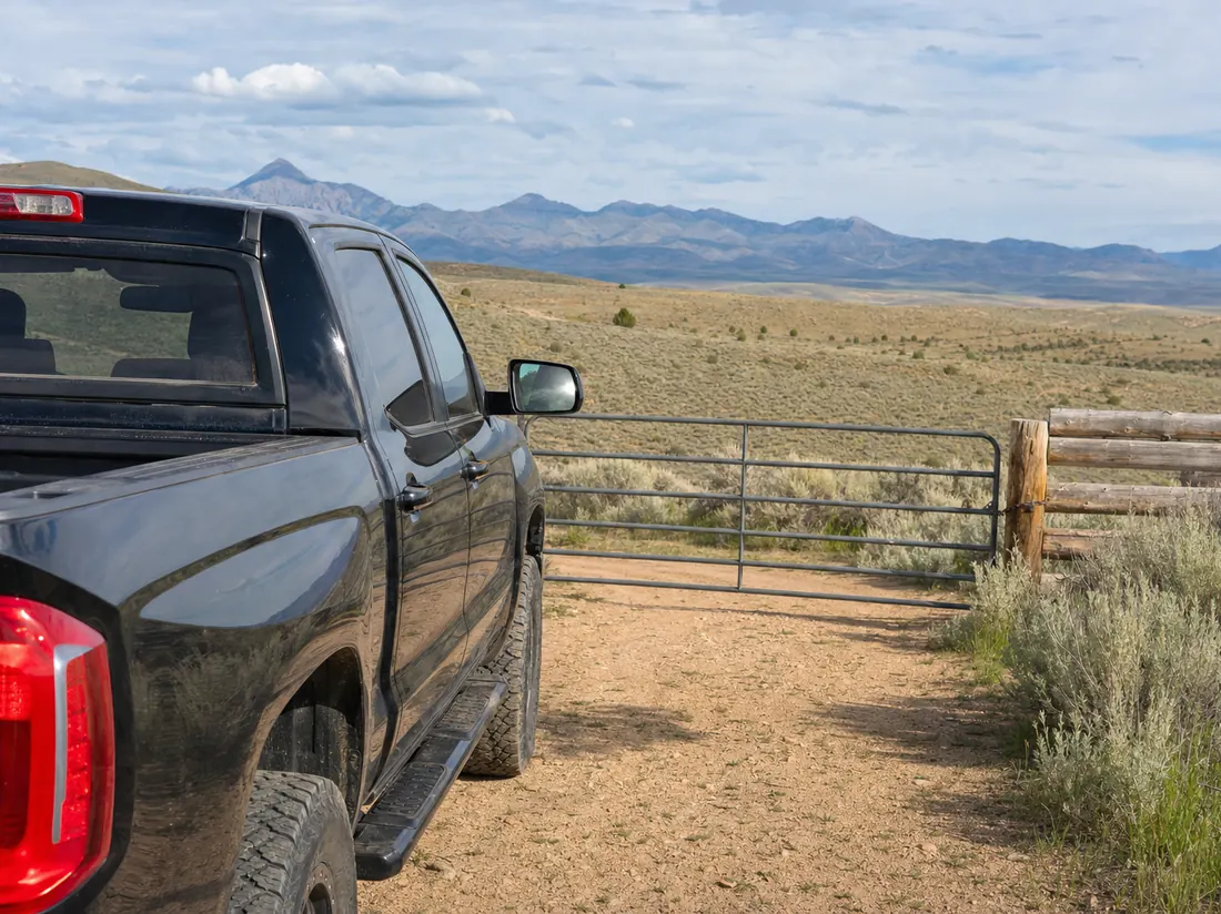 Pickup truck by a ranch gate in Idaho with sagebrush hills and distant mountains - selling a car in Idaho