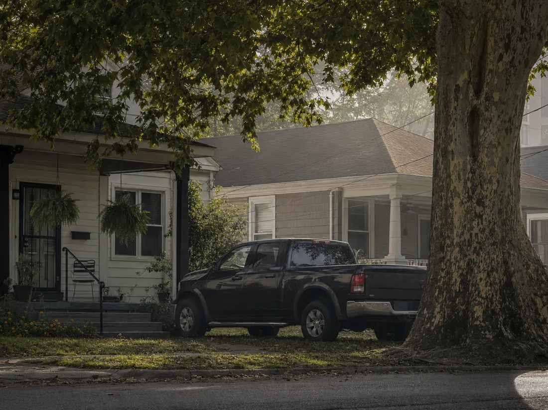 Pickup parked at a shotgun-style home in Evansville Indiana with river-valley humidity hanging in the air and a big sycamore - selling a car in Evansville