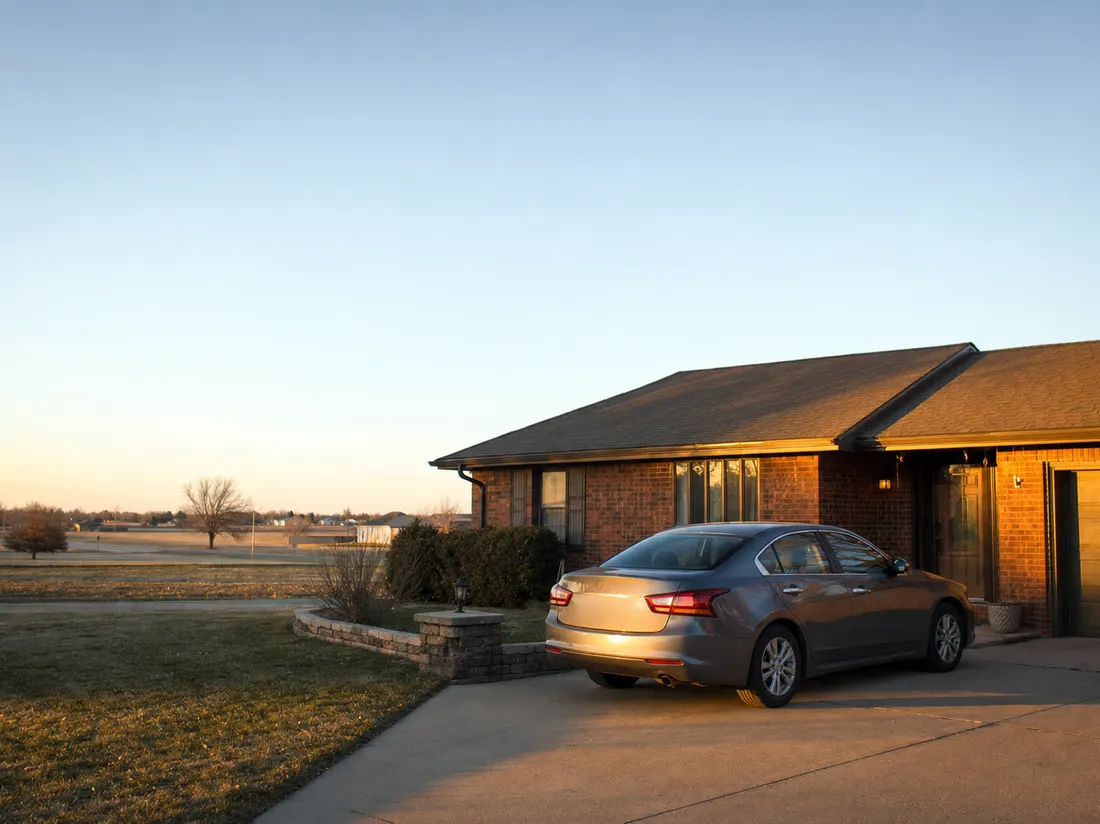 Sedan in the driveway of a brick ranch home in Wichita Kansas under an enormous flat prairie sky - selling a car in Wichita