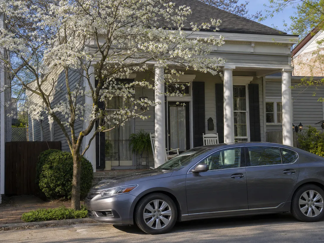 Sedan at a Louisville shotgun-style home with a porch, spring dogwoods blooming - selling a car in Louisville