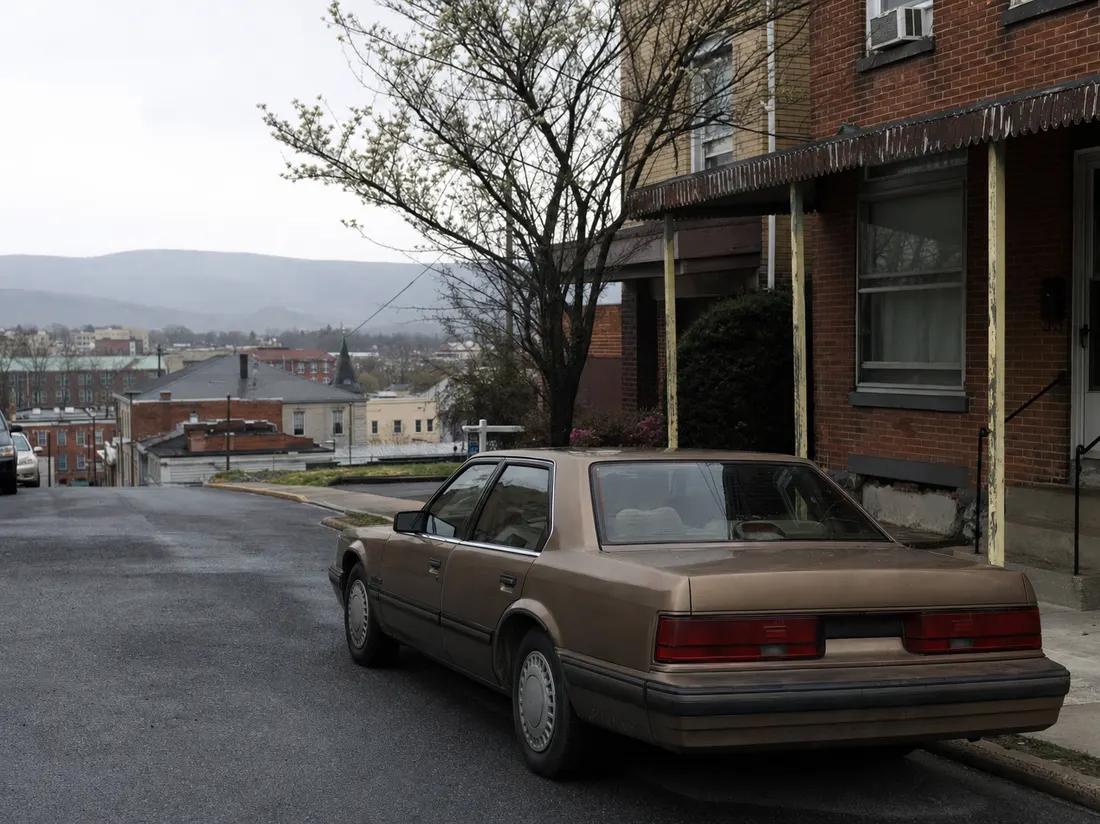 Older sedan by a brick rowhome in Hagerstown Maryland with South Mountain hazy in the distance - selling a car in Hagerstown