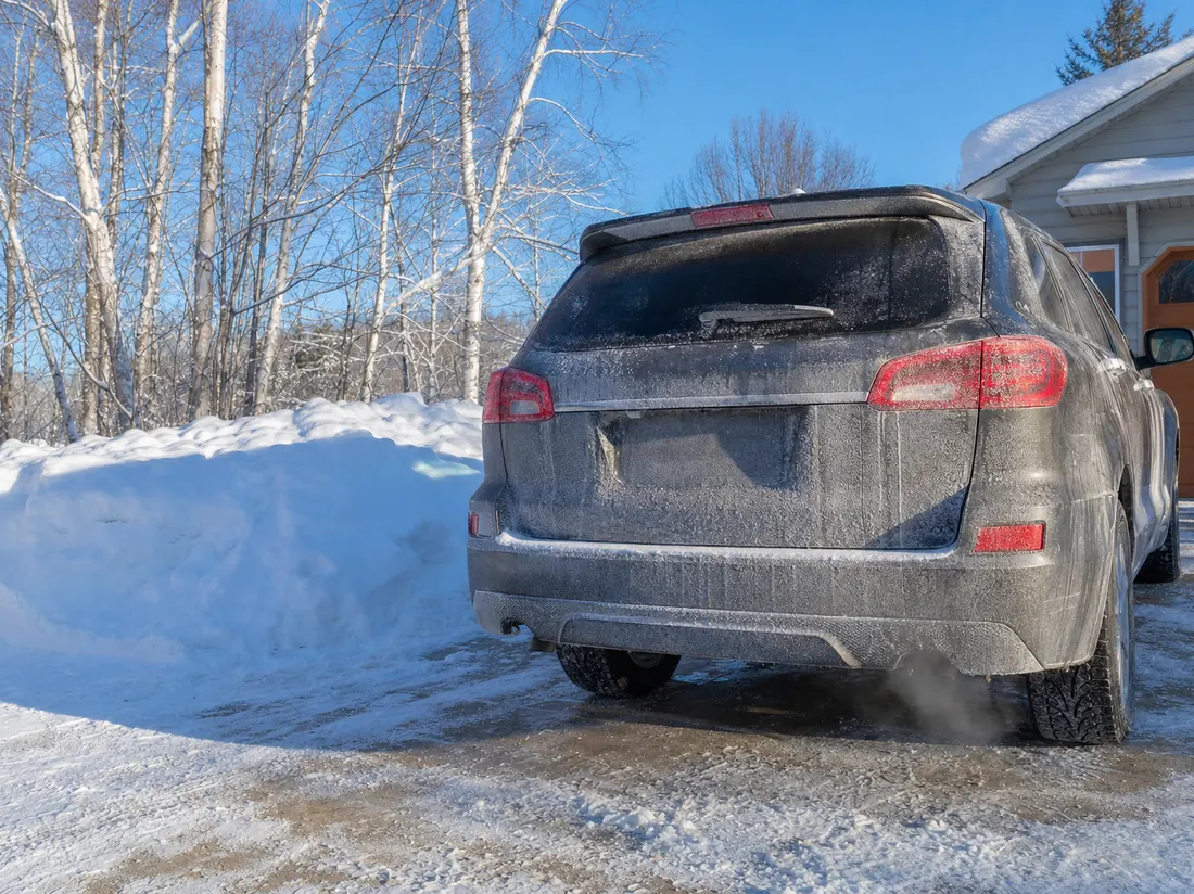 Road-salt-dusted SUV in a Minnesota driveway with high snowbanks and birch trees - selling a car in Minnesota