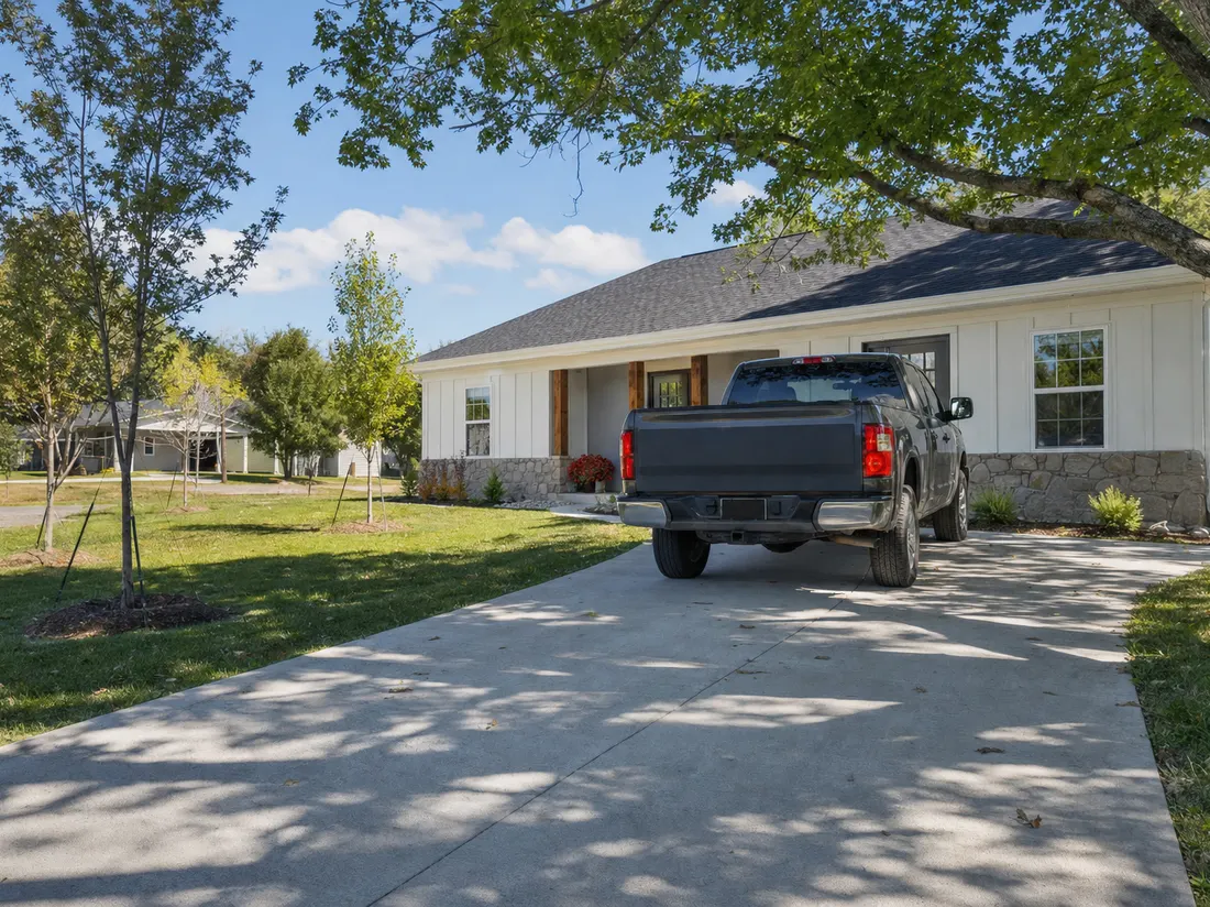Pickup in the driveway of a rebuilt one-story home in Joplin Missouri with young replacement trees along an open block - selling a car in Joplin