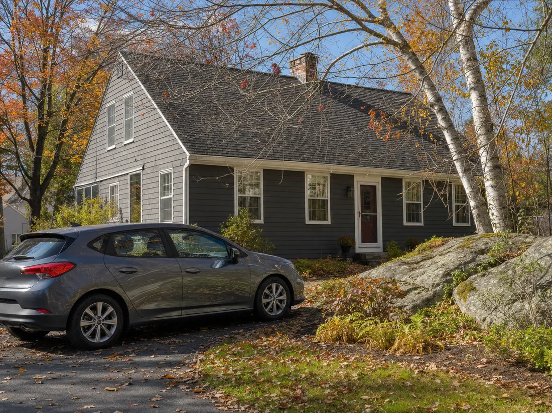 Hatchback beside a cape-style home in Concord New Hampshire with a granite outcrop in the yard and birches - selling a car in Concord