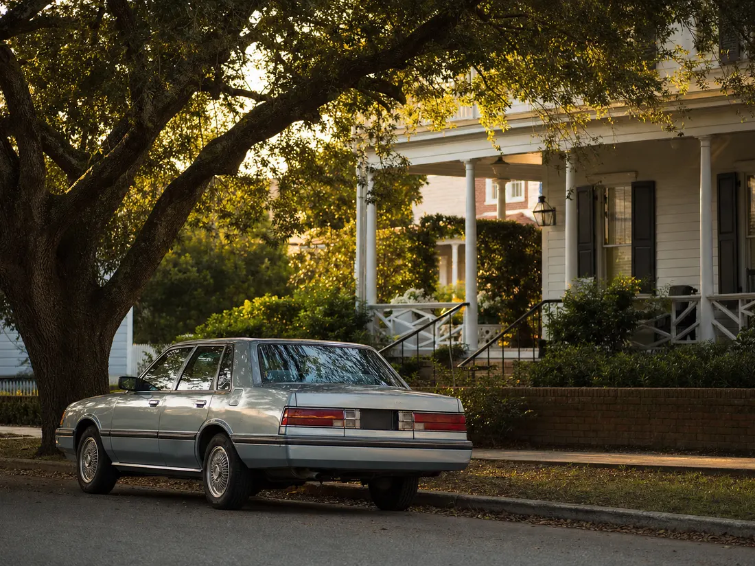 Older sedan beneath a live oak by a porch-fronted home in Wilmington North Carolina - selling a car in Wilmington