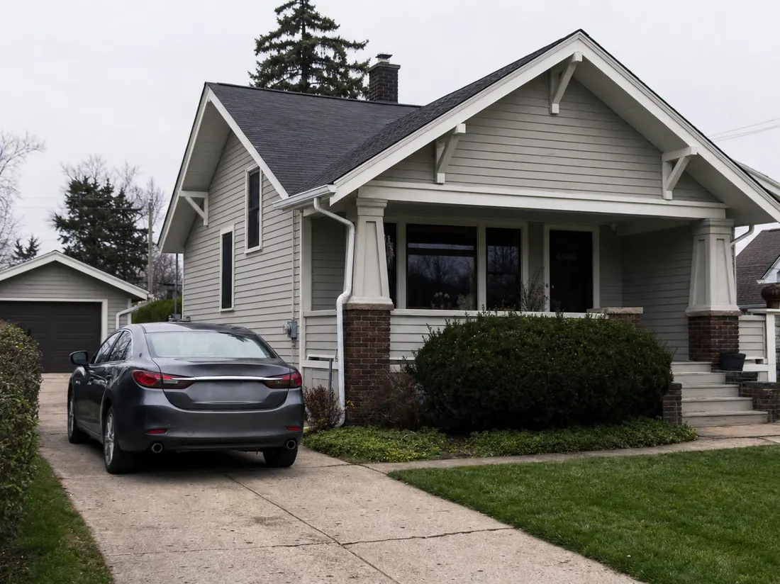 Sedan in the driveway of a Dayton craftsman bungalow with a detached garage - selling a car in Dayton