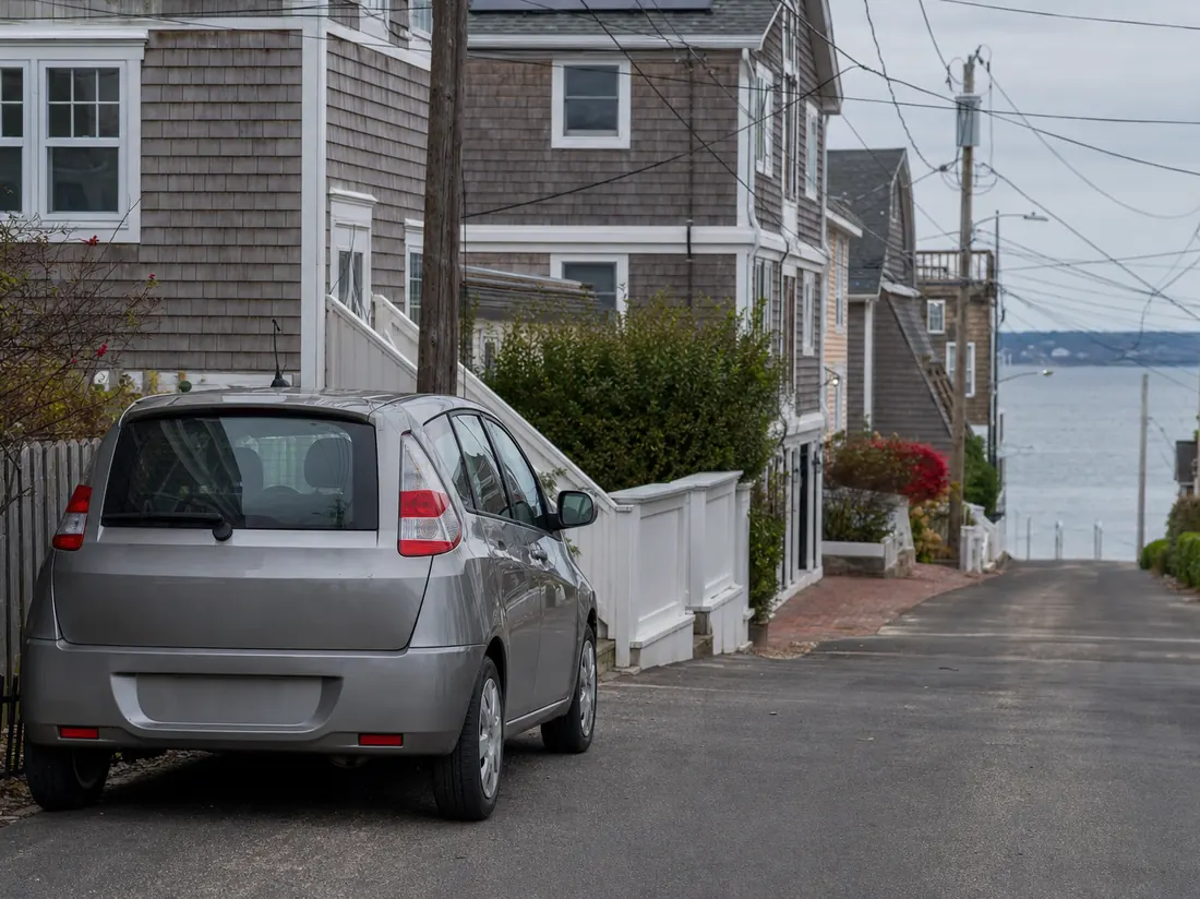 Compact car parked on a dense Rhode Island residential street with shingled houses near the coast - selling a car in Rhode Island