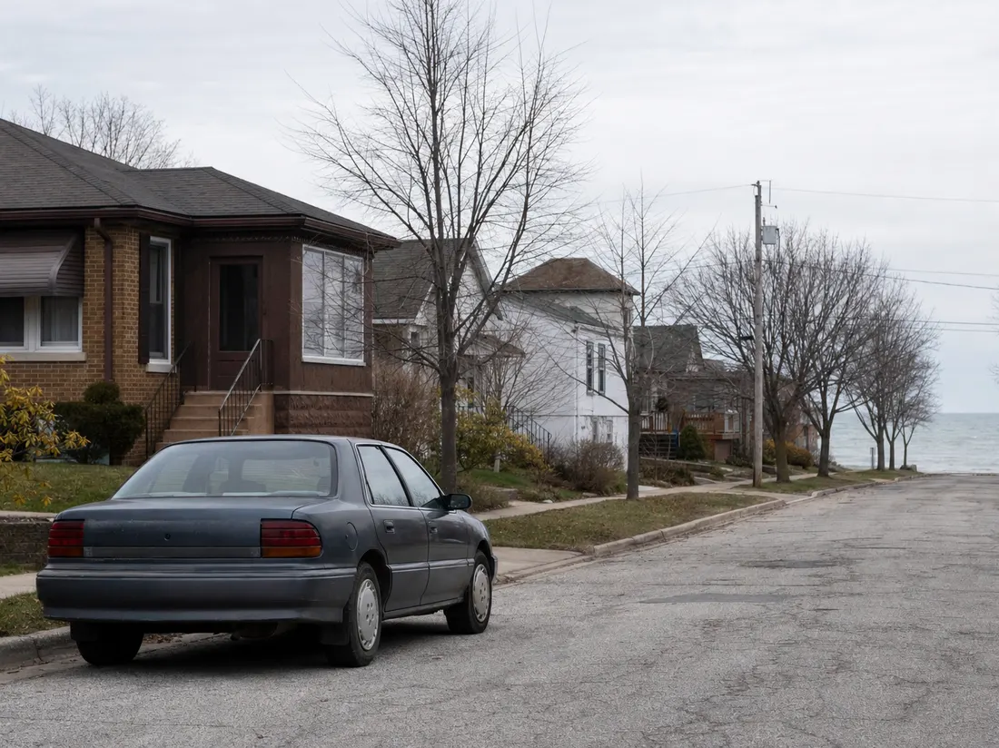 Older sedan outside a brick bungalow in Kenosha Wisconsin with Lake Michigan gray at the block's end - selling a car in Kenosha