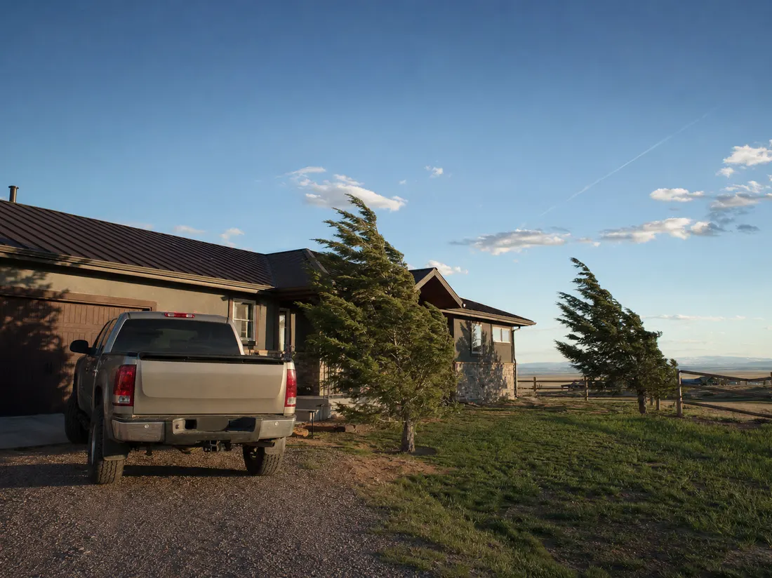 Pickup in the driveway of a ranch home in Cheyenne Wyoming with wind-bent trees and enormous plains sky - selling a car in Cheyenne